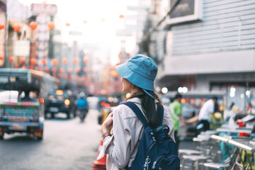 Fototapeta premium Rear view of walking young adult asian woman traveller backpack in city at street night market.