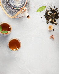 Asian teapot with herbal tea on light background.