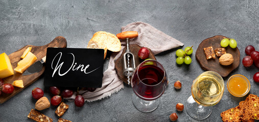 Red wine with appetizers on gray background.