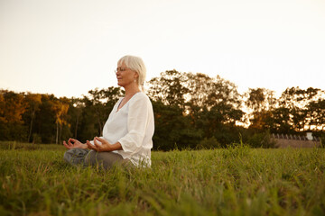 Meditation in the meadows. Shot of an attractive mature woman meditating in the outdoors at sunset.