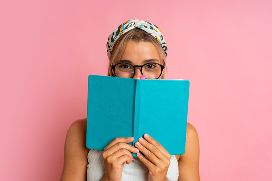 Studio Photo Of Pretty Blond  Student Woman With Suprice Face Posing With Note Book On Pink Background.