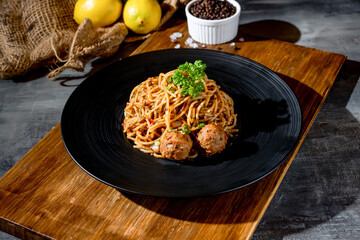 Classic Beef Bolognese pasta in a black dish with black pepper top view on dark background
