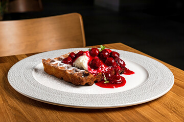 A waffle with whipped cream and cherry jam for breakfast, served on a big white plate