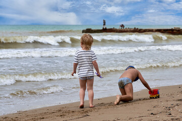 Two little boys are playing on the seashore - 490997850