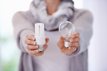 Keep the lights burning longer. A cropped image of a woman holding two different lightbulbs.
