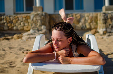 girl with closed eyes sunbathing on a sandy beach