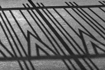 Geometric pattern fence shadow on sidewalk
