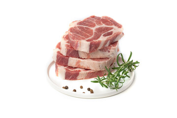 Pieces of marbled steak of raw pork or beef with a sprig of rosemary and pepper peas on a white plate on a white background.