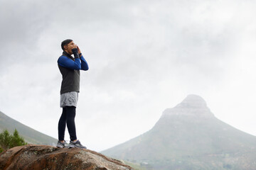 Waiting for the echo.... Shot of a young man shouting on a mountain top. - obrazy, fototapety, plakaty