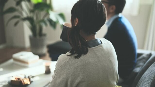 ソファーでくつろいでテレビを観る夫婦