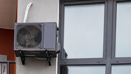 An air conditioning system installed outside on the wall of a brick building. Ventilation and air conditioning of housing.