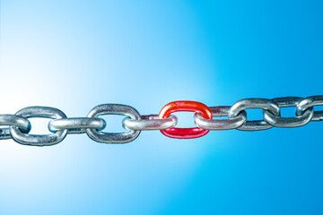 Iron chain with red link on blue background with copy space. Weak link concept.