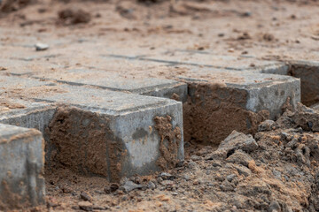 Fototapeta premium Pavement repair and laying of paving slabs on the walkway, stacked tile cubes on the background. Laying paving slabs in the pedestrian zone of the city, sand filling. Road tiles and curbs.