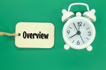 an alarm clock and a wooden tag with the word OVERVIEW
