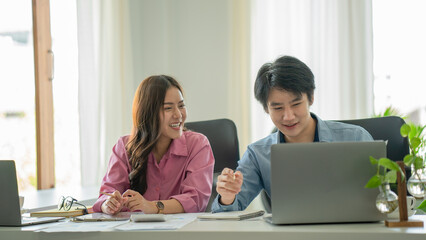 Young Asian couple or coworker working on laptop, casual business colleagues or information technology concept, with copy space