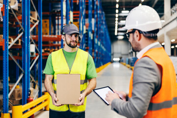 A supervisor and storage worker with box in hands agree about shipment.