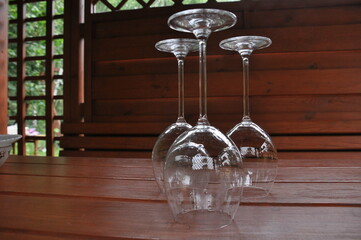 Glass wine glasses, standing on a wooden table in a gazebo in the countryside.