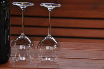 Glass wine glasses, standing on a wooden table in a gazebo in the countryside.
