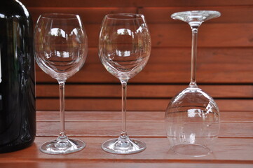 Glass wine glasses, standing on a wooden table in a gazebo in the countryside.