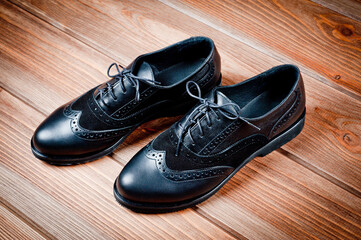 Black imitation leather shoes laced with wide laces. Close-up shot.