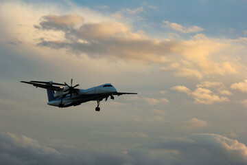 Naklejka na ściany i meble 空を飛行する夕日に染まった旅客機のシルエット「大阪空港」