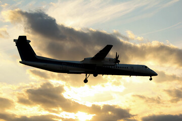 空を飛行する夕日に染まった旅客機のシルエット「大阪空港」