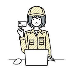 デスクで座ってPCを使いながらクレジットカードを手に持っている作業員の女性