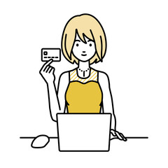 デスクで座ってPCを使いながらクレジットカードを手に持っているドレスの女性