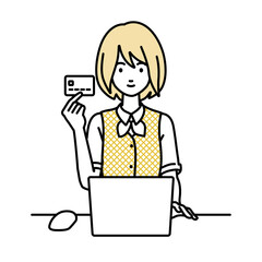 デスクで座ってPCを使いながらクレジットカードを手に持っている事務員制服の女性