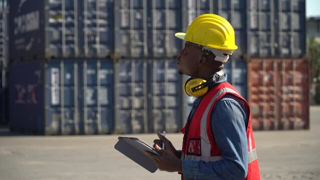 african american Foreman using tablet computer checking inventory control loading Containers at warehouse logistic in Cargo freight ship for import export. engineer and transportation hot in sun light