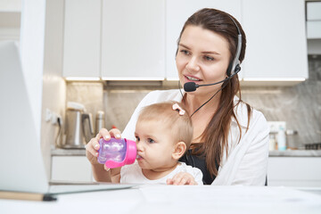 Mother feeding her daughter from baby bottle while working