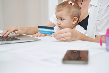 Baby looking at laptop with adult holding debit card