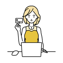 デスクで座ってPCを使いながらクレジットカードを手に持っているドレスの女性