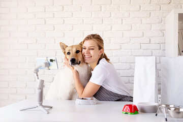 Young caucasian woman groomer blogger speaking looking to camera, having stream with her dog