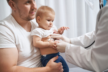 Physician listening to kid breathing through stethoscope