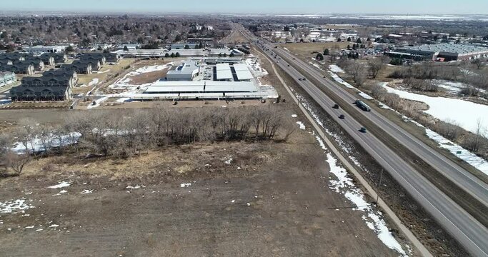 Highway parallel flight showing affordable housing car dealership and empty space drone shot 4k