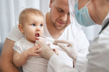 Baby opening mouth for doctor with spatula