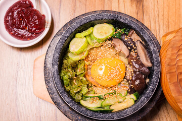 Bibimbap in a black heated stone bowl, Korean traditional dish- bibimbap mixed rice with vegetables Include beef and fried egg, Japanese hot pot food