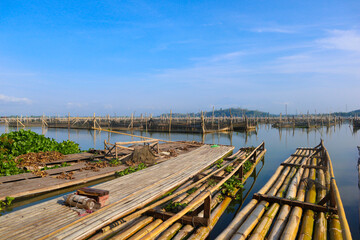 Fototapeta na wymiar bamboo raft leaning against a lake among traditional fish cages in indonesia, asia