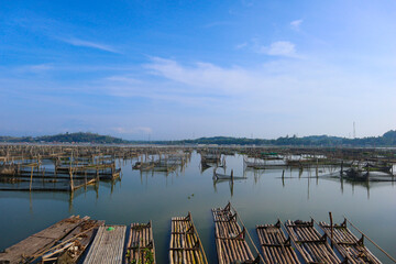 bamboo raft leaning against a lake among traditional fish cages in indonesia, asia