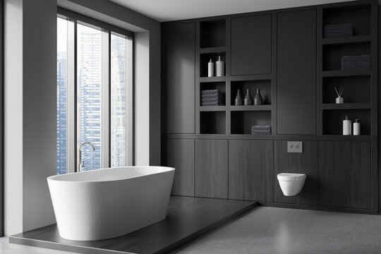 Grey bathroom interior with tub, toilet and shelf, window with city view