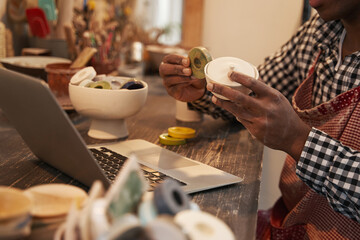 Ceramist demonstrating pair of earthenware products to customer