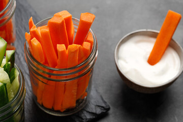Dipping yogurt sauce and carrot sticks in glass jar. Healthy food