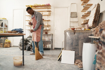 Cheerful ceramist doing cleaning in pottery studio