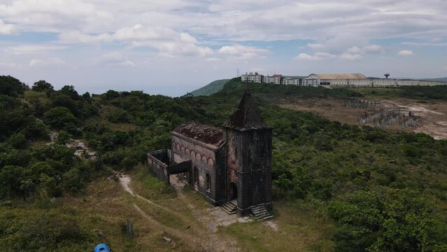 Historic ruined church of the French colonial buildings of former mountain resort atop Bokor Mountain in Preah Monivong National Park on a cloudy day. Backwards drone dolly shot