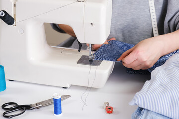Seamstress makes a seam on an electric sewing machine. Close-up of hands. Tailor workflow details.