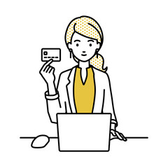 デスクで座ってPCを使いながらクレジットカードを手に持っているジャケットの女性
