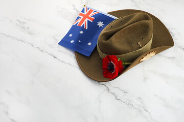 Anzac army slouch hat with Australian Flag and Poppy on stone background