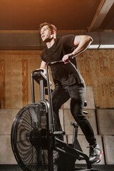 Fototapeta na wymiar man using exercise bike at the gym. Fitness male using air bike for cardio workout at gym.