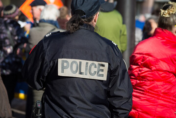 Colmar - France - 5 March 2022 - portrait on back view of french national policewoman walking in the street during a protesting march